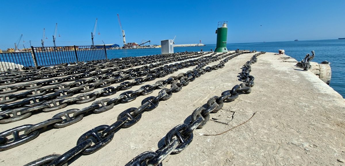 Ocho paños de cadena con contrete extendidos en paralelo sobre el molo de un puerto, listos para su revisión dimensional antes del embarque.
